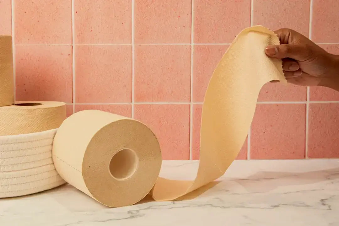 A roll of Hey Bamboo against a pink tile wall