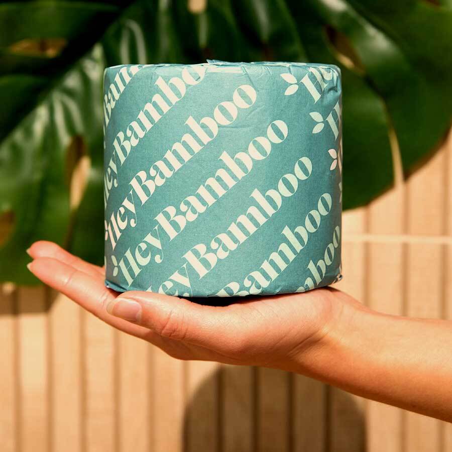 A hand folds a roll of hey bamboo wrapped in teal paper on their palm